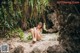 A woman in a blue bikini sitting on a rock.