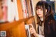 A woman standing in front of a bookshelf holding a book.