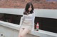 A woman sitting on a ledge next to a brick wall.