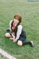 A young woman sitting on a soccer field.