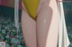 A woman in a yellow bikini standing in front of a crowd.