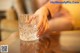 A woman's hand holding a glass of water on a table.